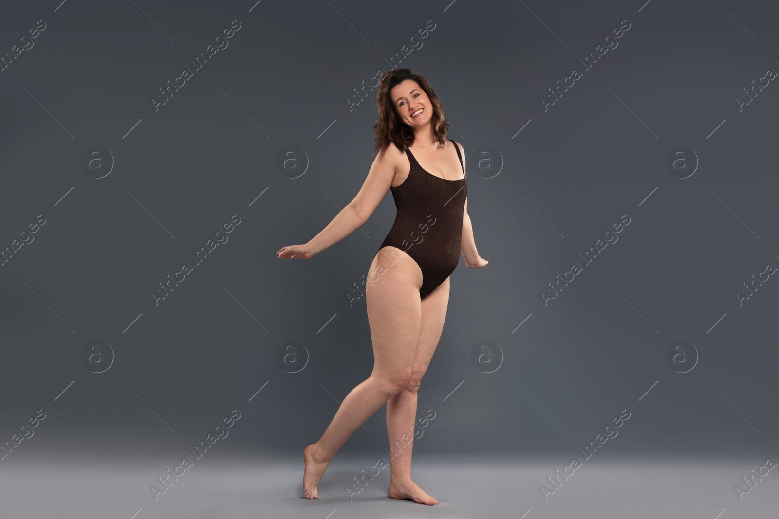 Photo of Beautiful woman in bodysuit on dark grey background. Cellulite problem