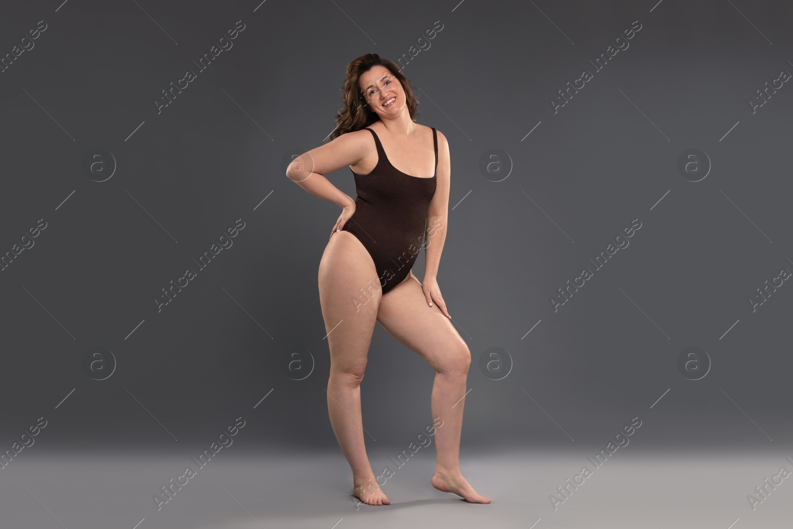 Photo of Beautiful woman in bodysuit on dark grey background. Cellulite problem