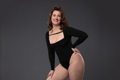 Photo of Beautiful woman in bodysuit on dark grey background. Cellulite problem