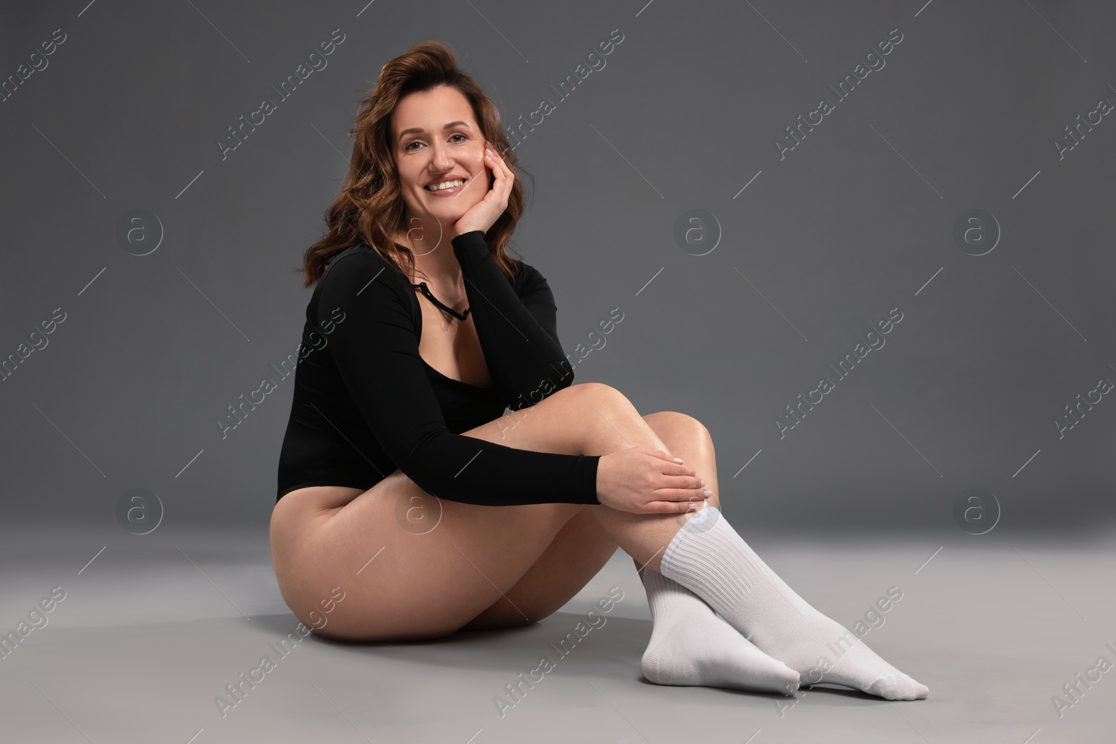 Photo of Beautiful woman in bodysuit on dark grey background. Cellulite problem