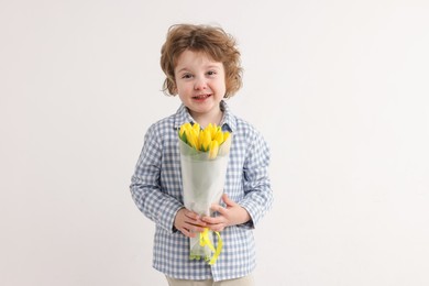 Photo of Cute little boy with bouquet of tulips on white background