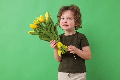 Photo of Cute little boy with bouquet of tulips on green background