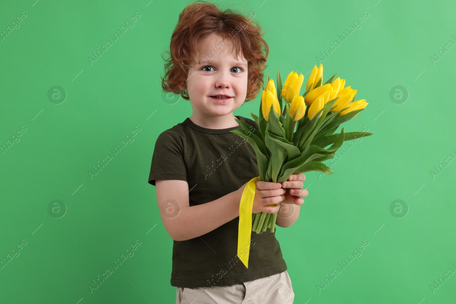 Photo of Cute little boy with bouquet of tulips on green background