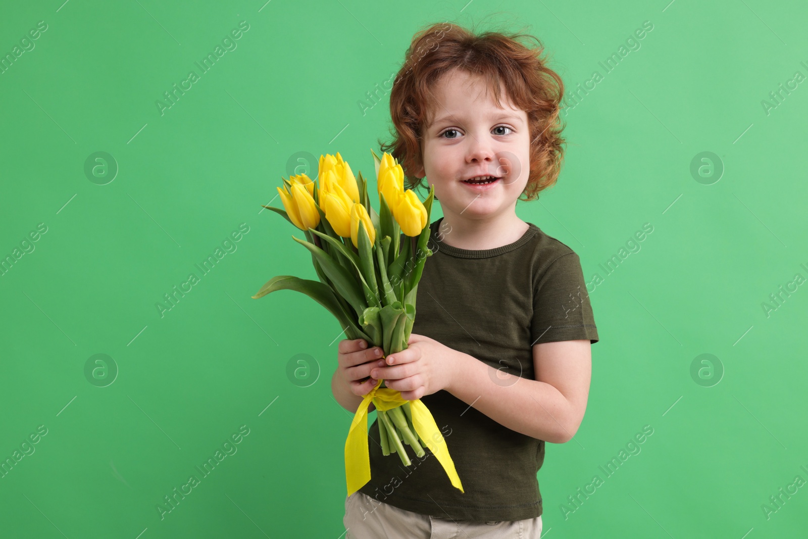 Photo of Cute little boy with bouquet of tulips on green background