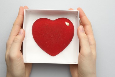 Photo of Woman with heart shaped chocolate in box on white background, top view