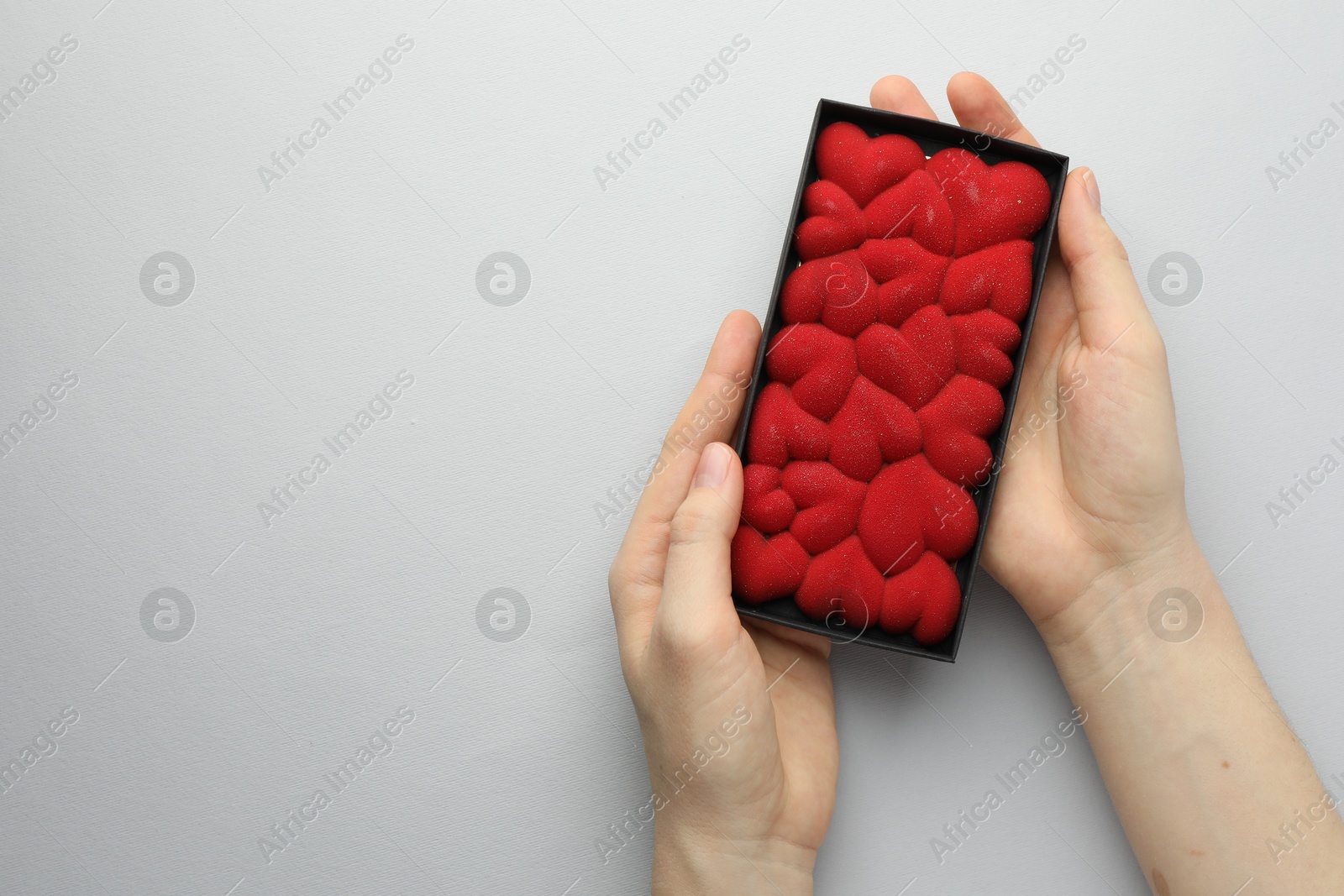 Photo of Woman holding chocolate bar decorated with hearts on white background, top view. Space for text