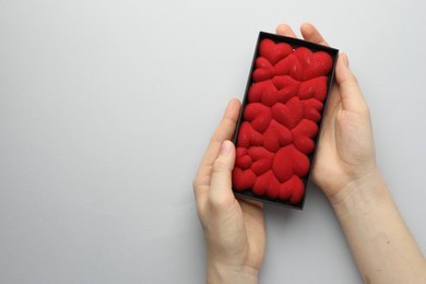 Photo of Woman holding chocolate bar decorated with hearts on white background, top view. Space for text