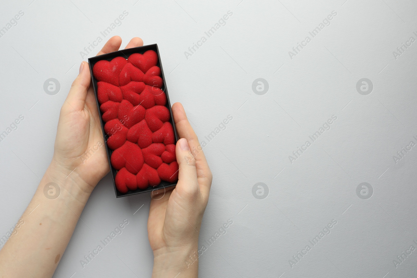 Photo of Woman holding chocolate bar decorated with hearts on white background, top view. Space for text