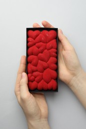 Photo of Woman holding chocolate bar decorated with hearts on white background, top view