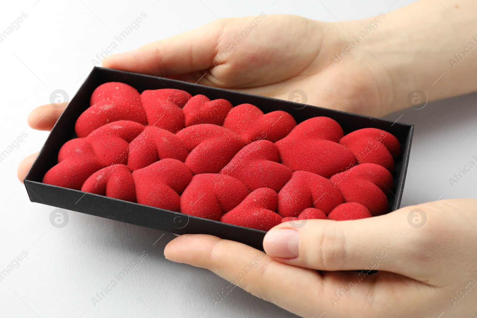 Photo of Woman holding chocolate bar decorated with hearts on white background, closeup