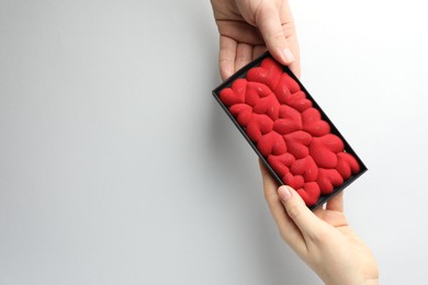 Photo of Man gifting woman chocolate bar decorated with hearts on white background, closeup. Space for text