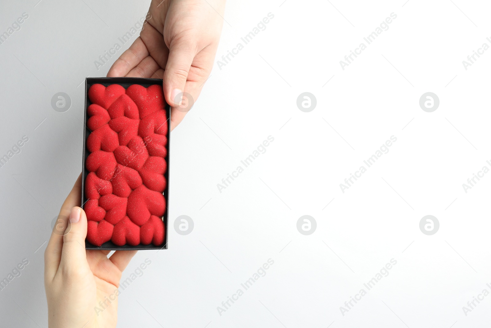 Photo of Man gifting woman chocolate bar decorated with hearts on white background, closeup. Space for text