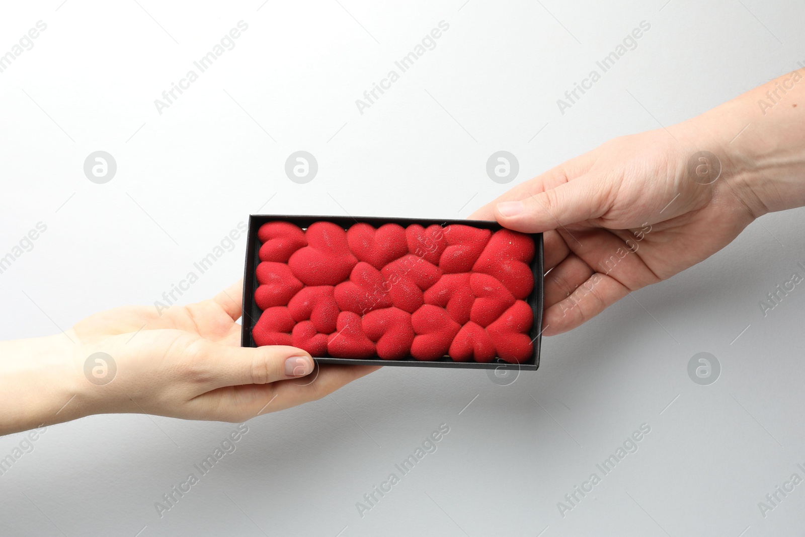 Photo of Man gifting woman chocolate bar decorated with hearts on white background, closeup