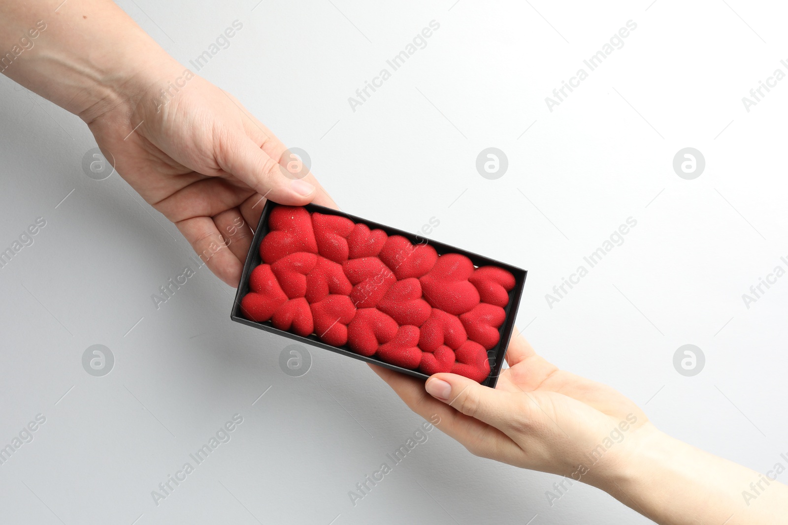 Photo of Man gifting woman chocolate bar decorated with hearts on white background, closeup