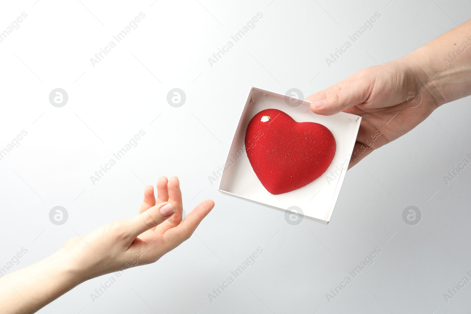 Photo of Man gifting woman heart shaped chocolate on white background, closeup. Space for text