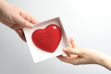 Photo of Man gifting woman heart shaped chocolate on white background, closeup