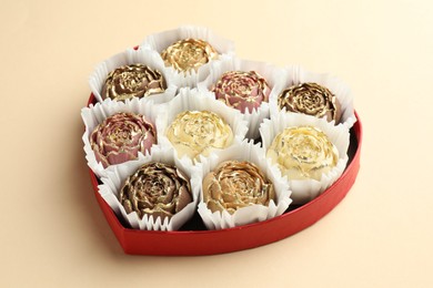 Photo of Flower shaped chocolate bonbons in box on beige background, closeup