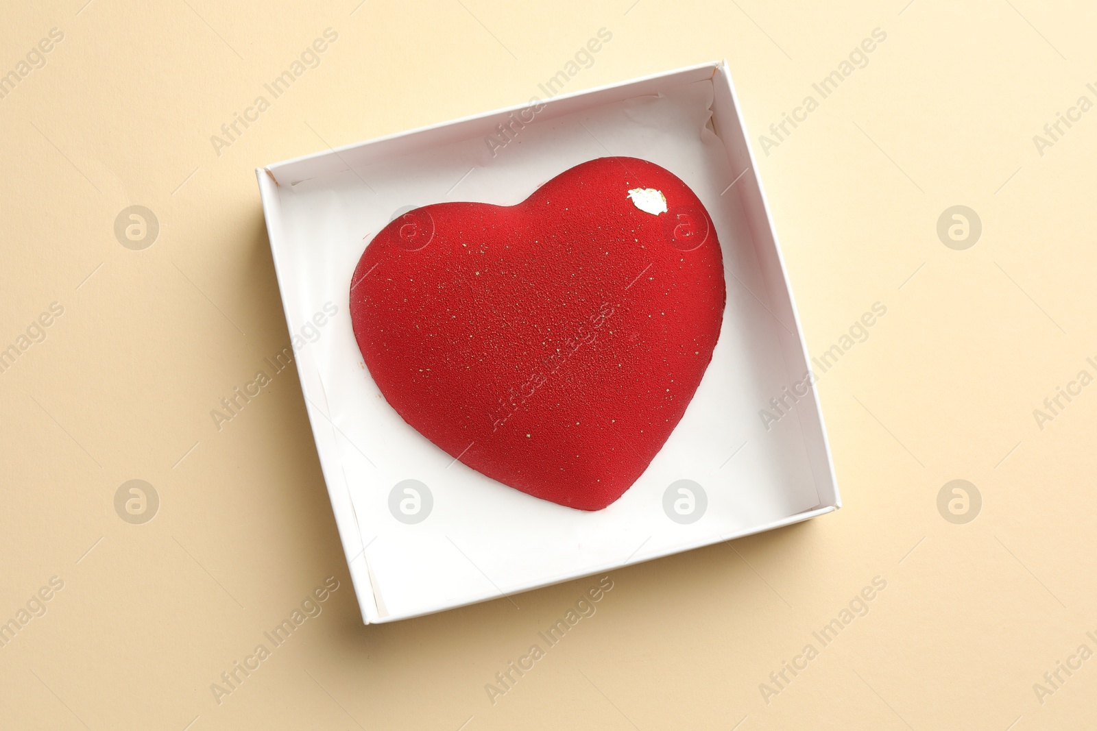 Photo of Heart shaped chocolate in box on beige background, top view