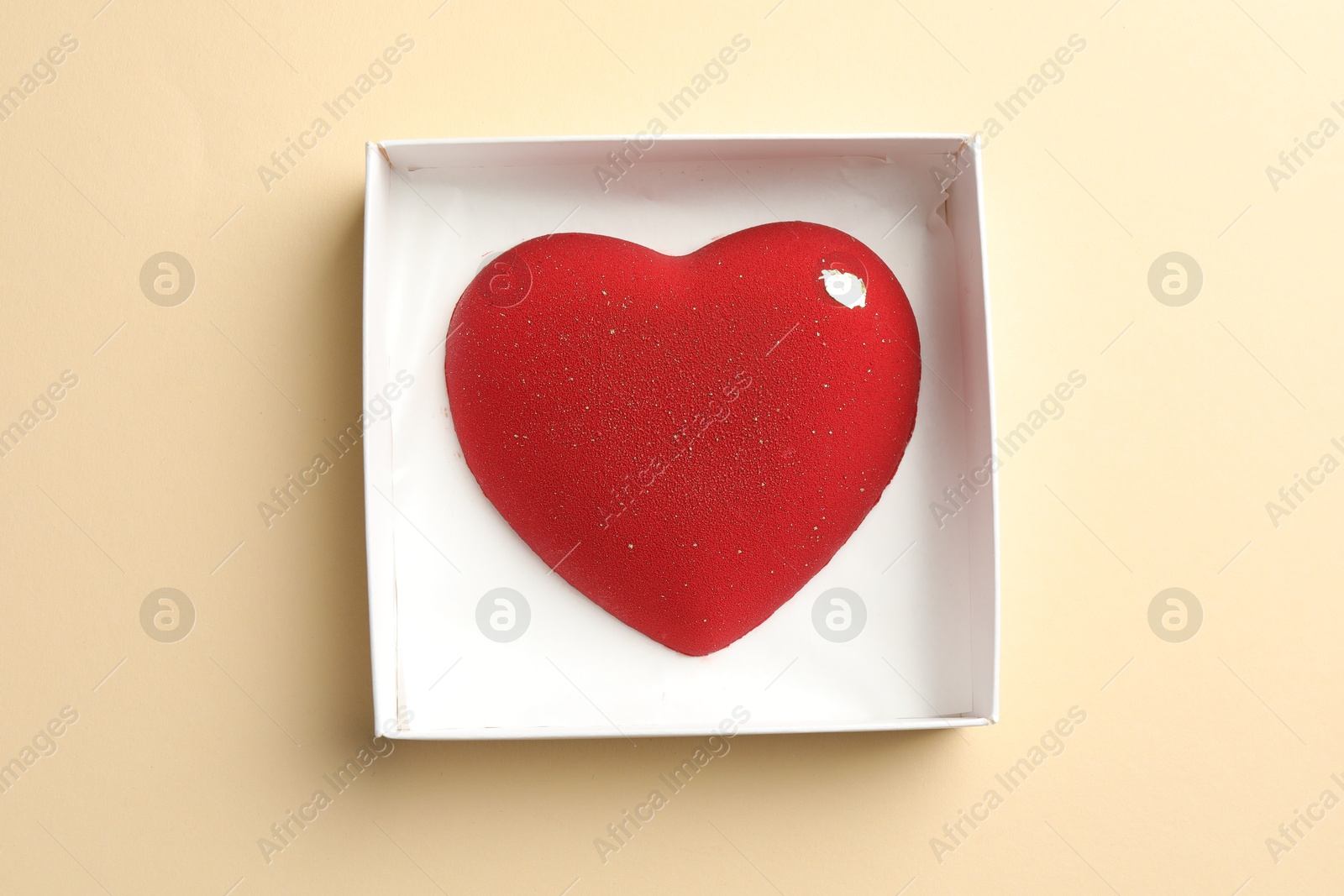 Photo of Heart shaped chocolate in box on beige background, top view