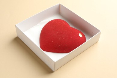 Photo of Heart shaped chocolate in box on beige background, closeup