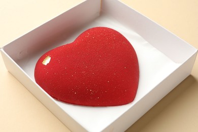 Photo of Heart shaped chocolate in box on beige background, closeup