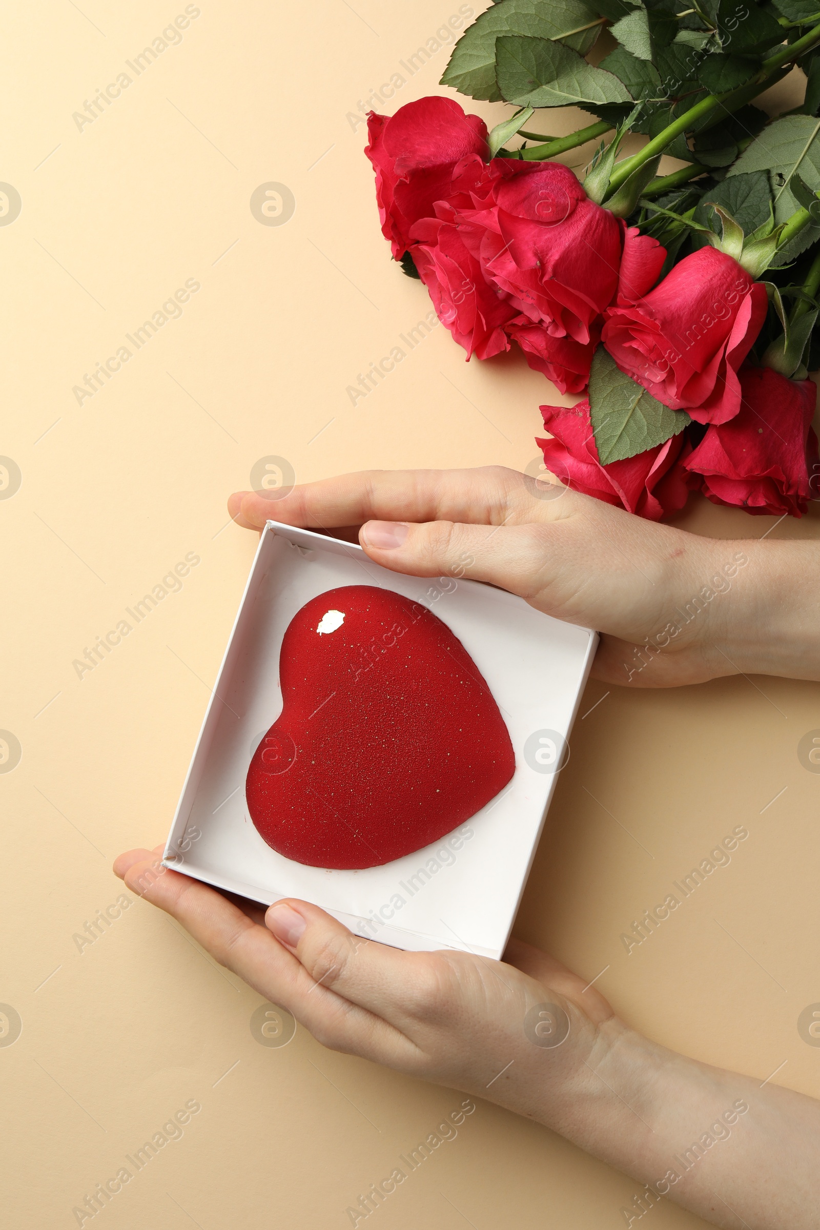 Photo of Woman with heart shaped chocolate and roses on beige background, top view