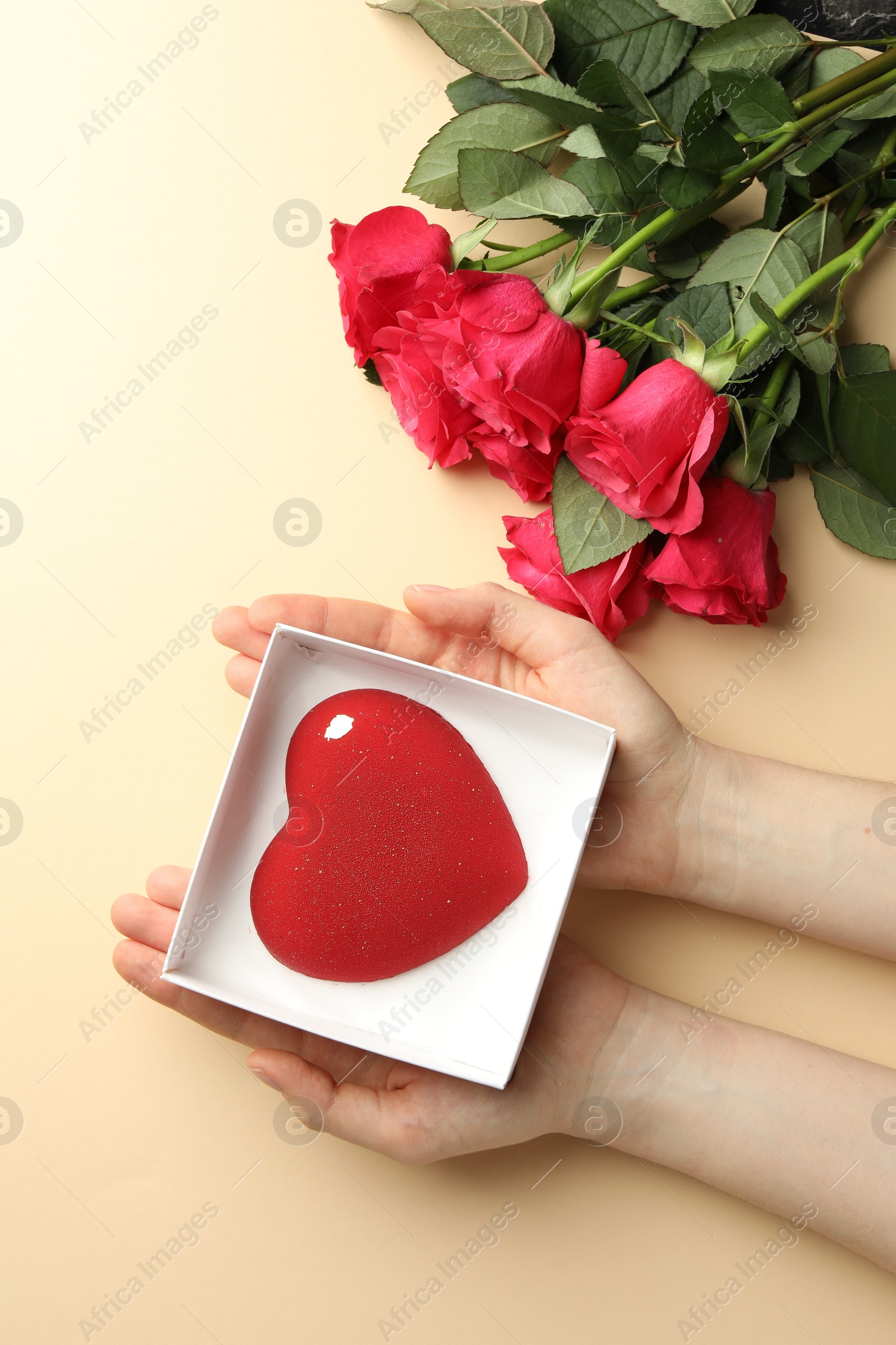 Photo of Woman with heart shaped chocolate and roses on beige background, top view