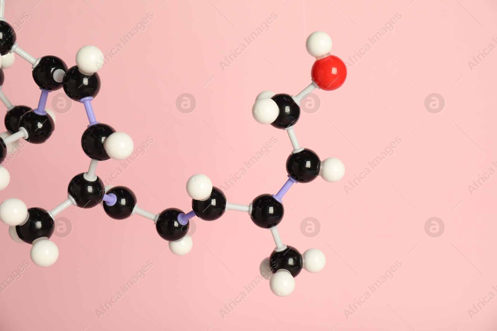 Photo of Molecule of retinol (vitamin A) on pink background, closeup. Chemical model