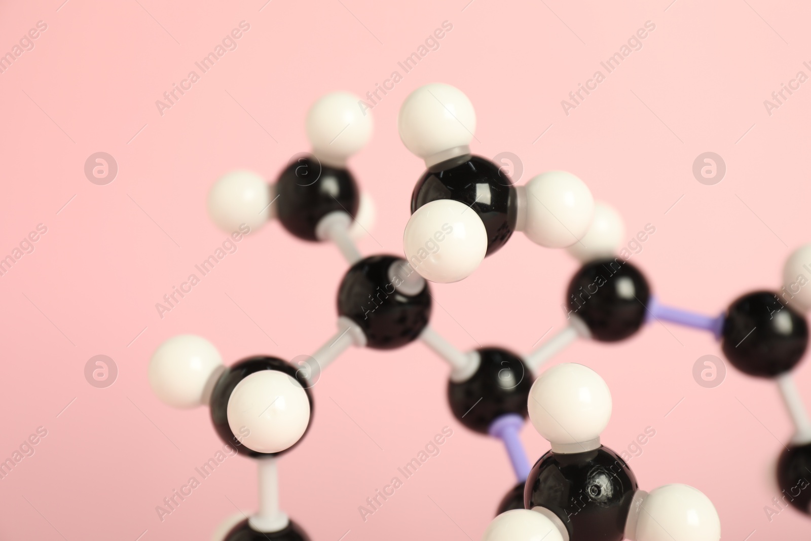 Photo of Molecule of retinol (vitamin A) on pink background, closeup. Chemical model