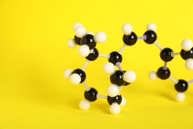 Photo of Molecule of retinol (vitamin A) on yellow background, closeup and space for text. Chemical model