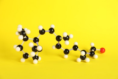 Photo of Molecule of retinol (vitamin A) on yellow background. Chemical model