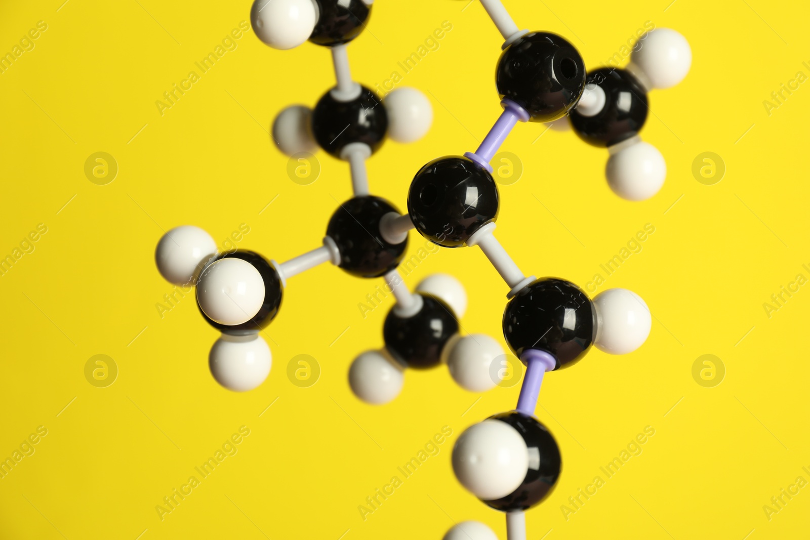 Photo of Molecule of retinol (vitamin A) on yellow background, closeup. Chemical model