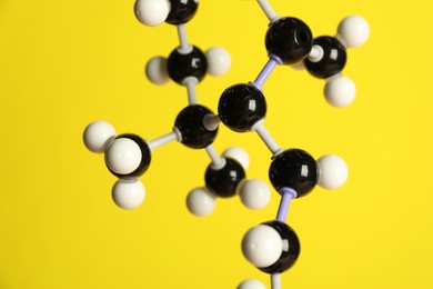 Photo of Molecule of retinol (vitamin A) on yellow background, closeup. Chemical model