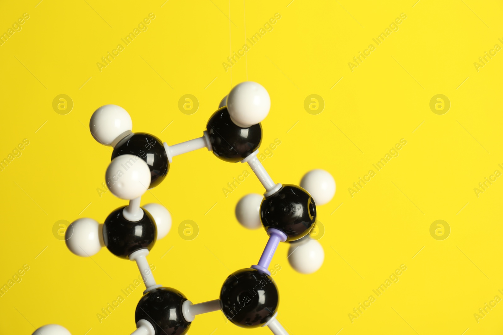 Photo of Molecule of retinol (vitamin A) on yellow background, closeup and space for text. Chemical model