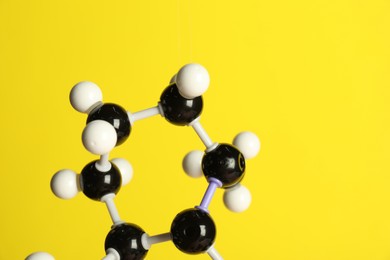 Photo of Molecule of retinol (vitamin A) on yellow background, closeup and space for text. Chemical model