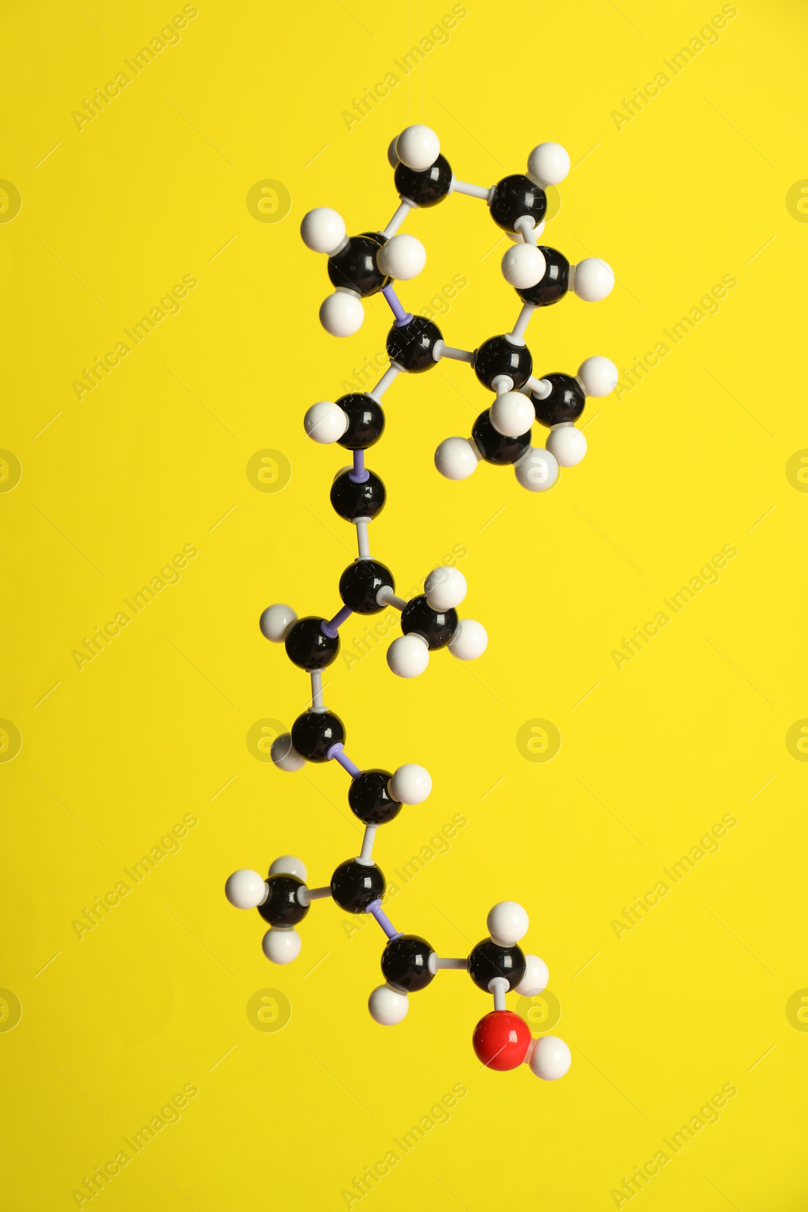 Photo of Molecule of retinol (vitamin A) on yellow background. Chemical model