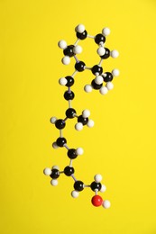 Photo of Molecule of retinol (vitamin A) on yellow background. Chemical model