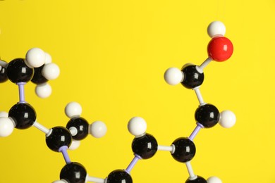 Photo of Molecule of retinol (vitamin A) on yellow background, closeup. Chemical model