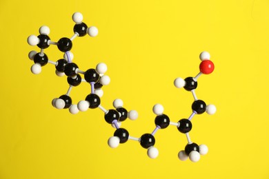 Photo of Molecule of retinol (vitamin A) on yellow background. Chemical model