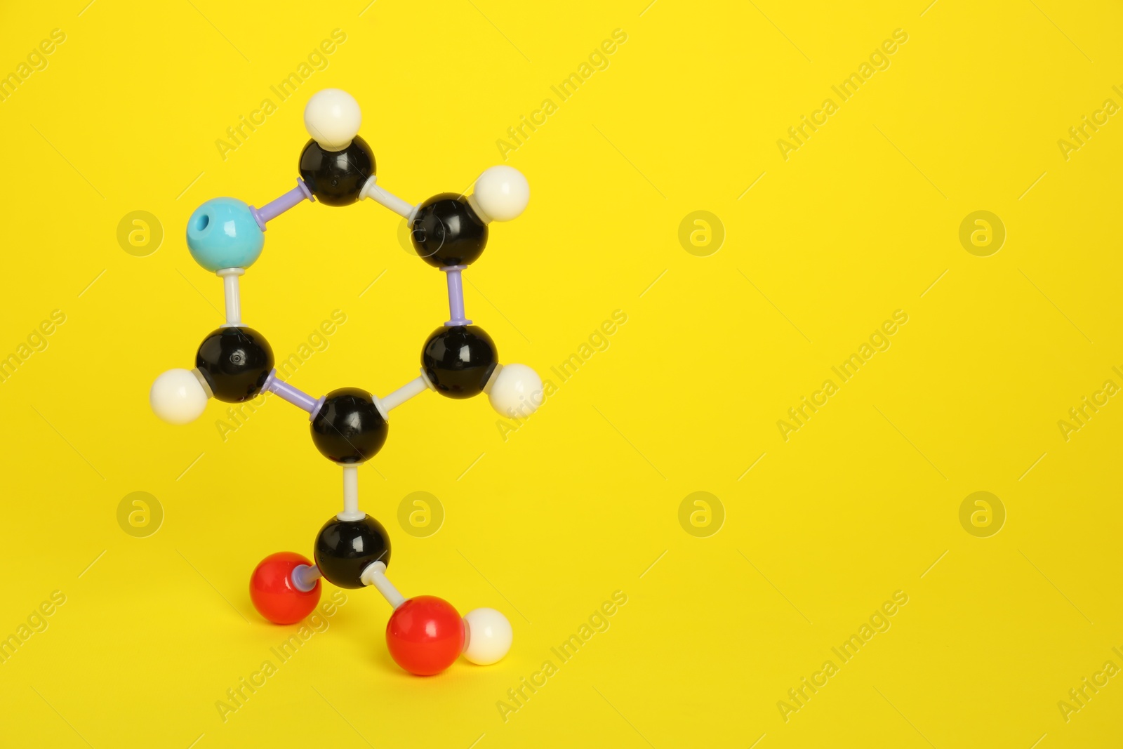 Photo of Molecule of niacin (vitamin B3) on yellow background, space for text. Chemical model