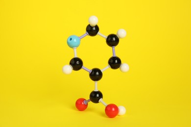 Photo of Molecule of niacin (vitamin B3) on yellow background. Chemical model