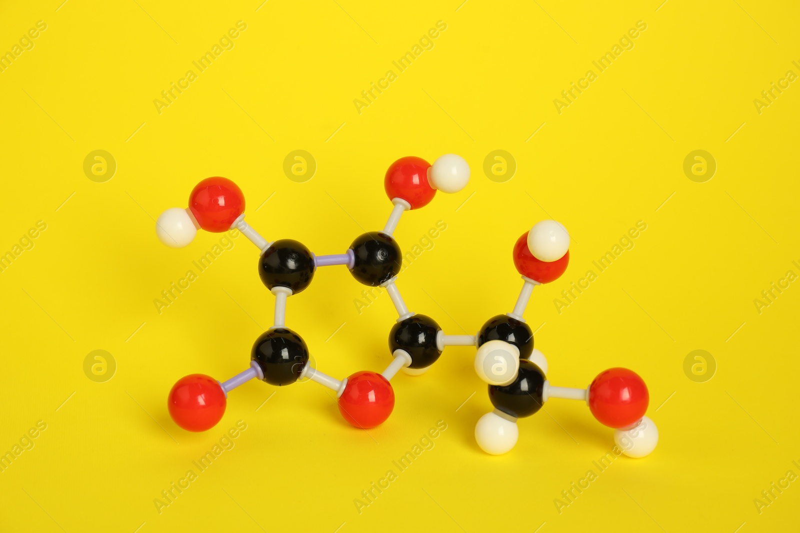 Photo of Molecule of vitamin C on yellow background. Chemical model