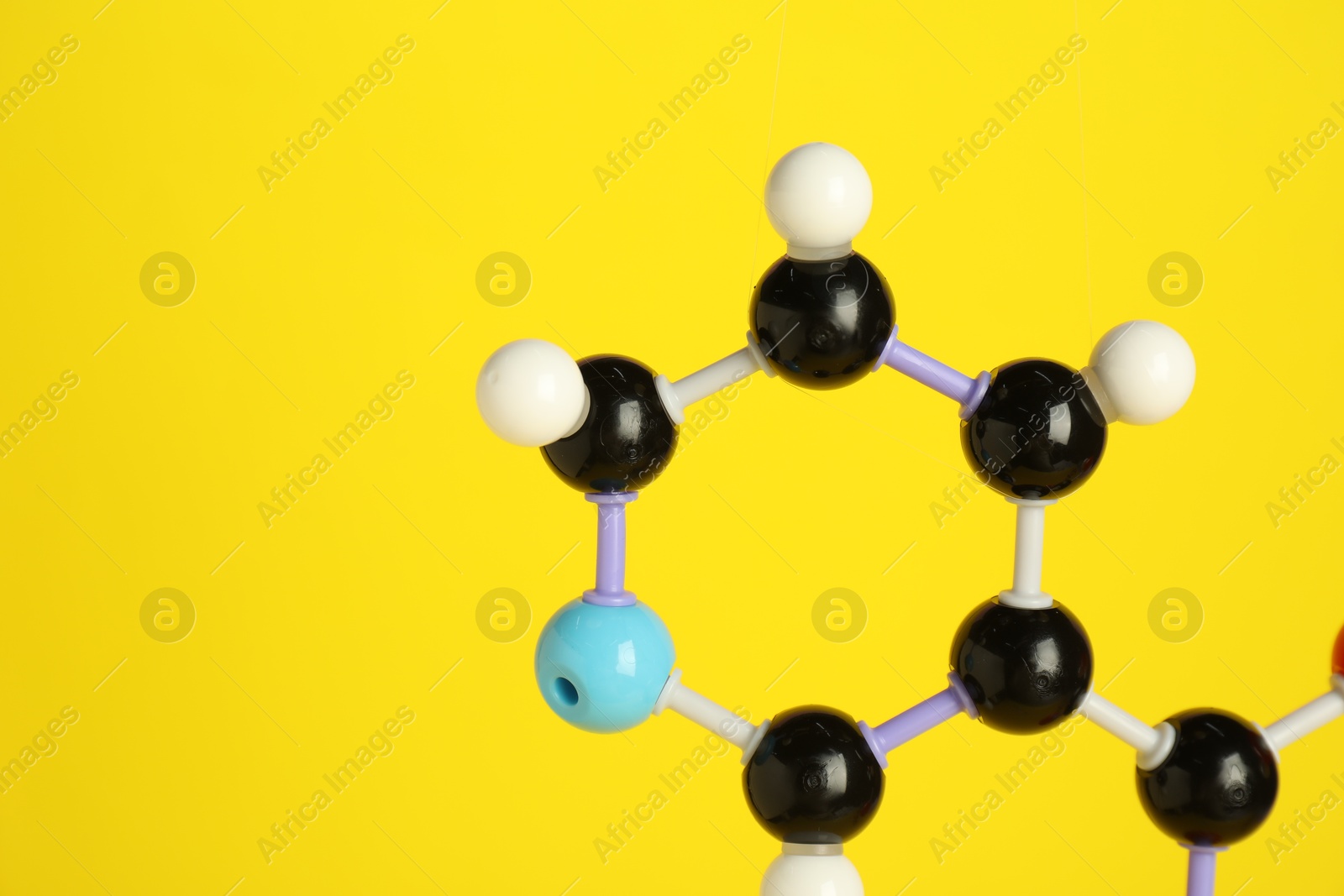 Photo of Molecule of niacin (vitamin B3) on yellow background, closeup and space for text. Chemical model