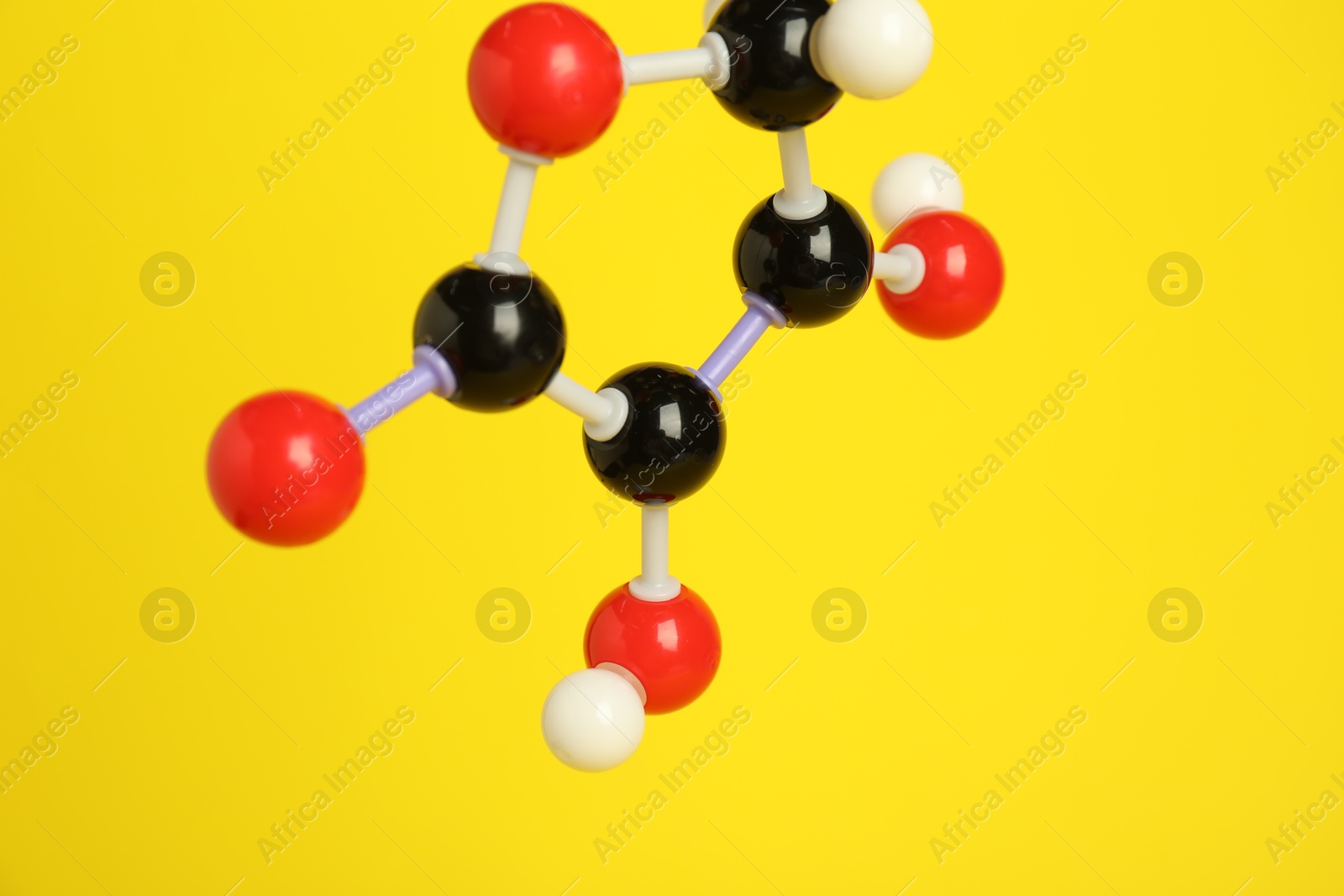 Photo of Molecule of vitamin C on yellow background, closeup. Chemical model