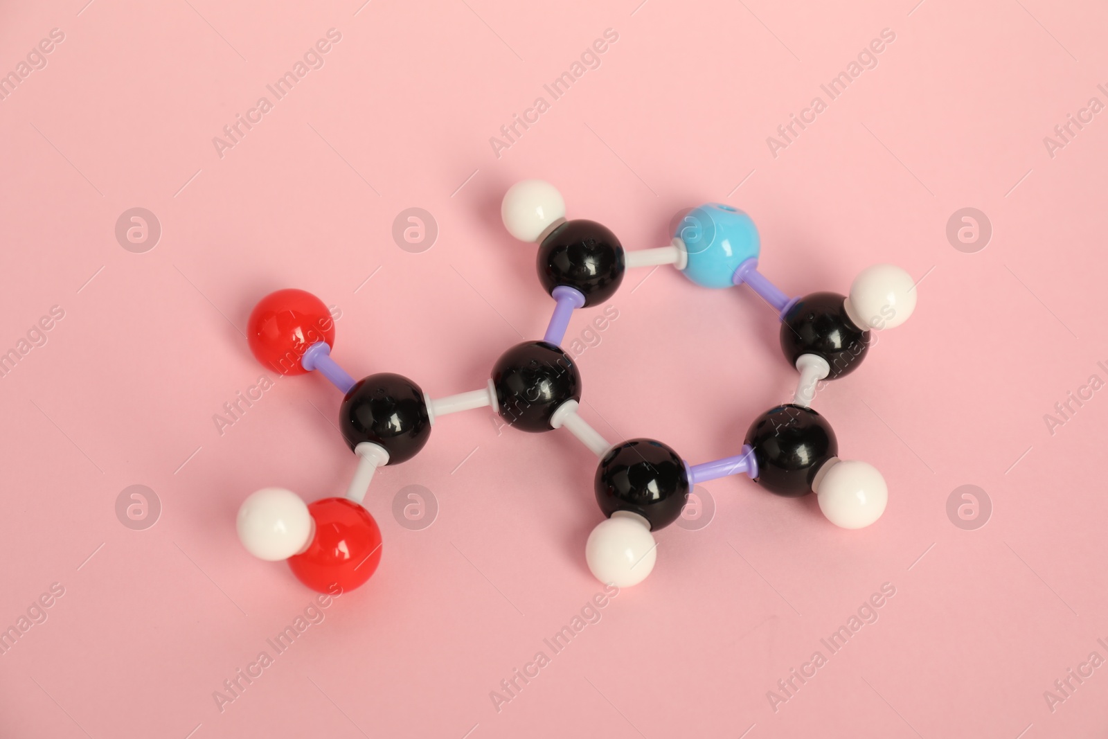 Photo of Molecule of niacin (vitamin B3) on pink background. Chemical model