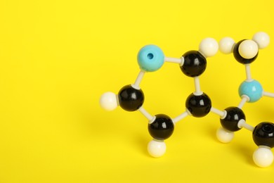 Photo of Chemical model of molecule on yellow background, closeup. Space for text