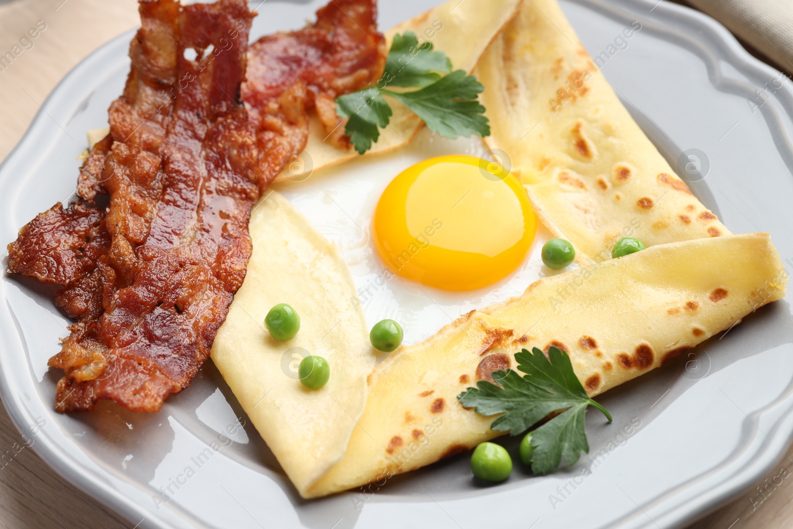 Photo of Delicious crepe with egg, bacon and green peas on table, closeup. Breton galette