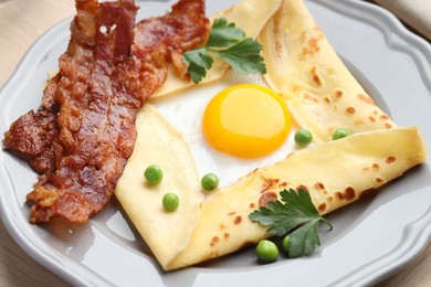 Photo of Delicious crepe with egg, bacon and green peas on table, closeup. Breton galette