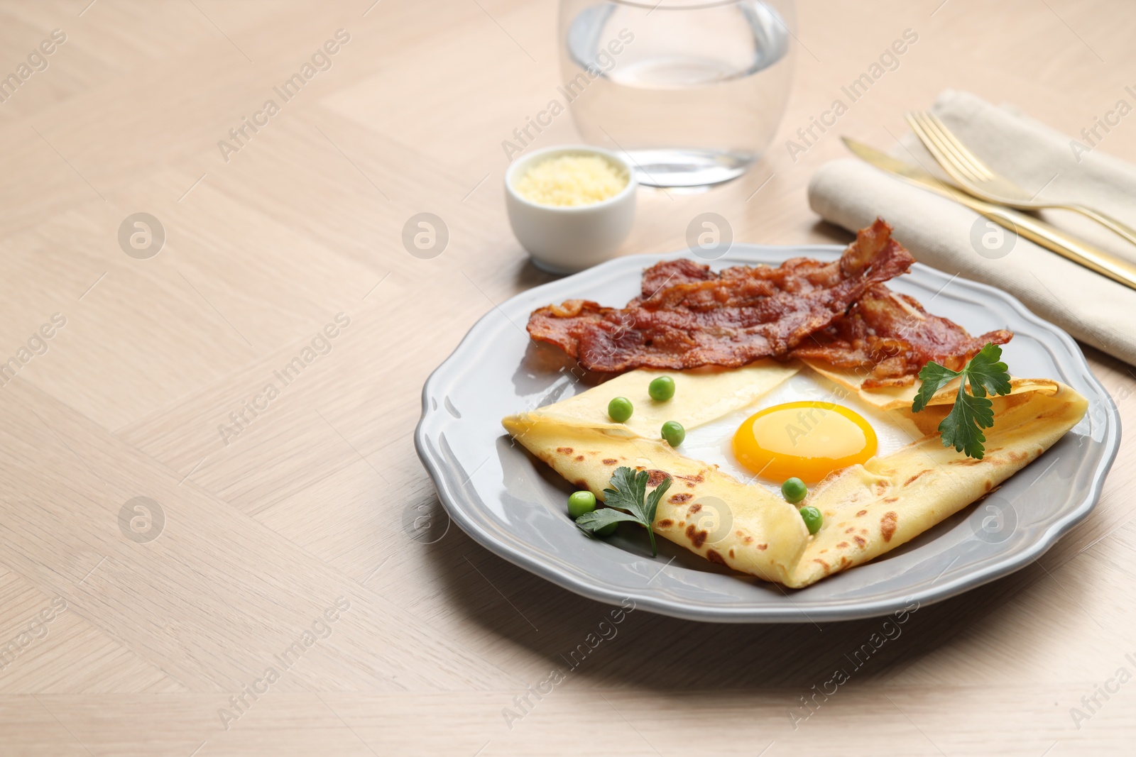 Photo of Delicious crepe with egg, bacon and green peas served on wooden table, space for text. Breton galette