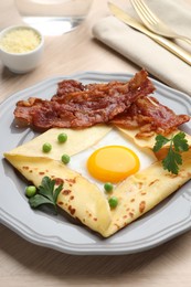 Photo of Delicious crepe with egg, bacon and green peas served on wooden table. Breton galette